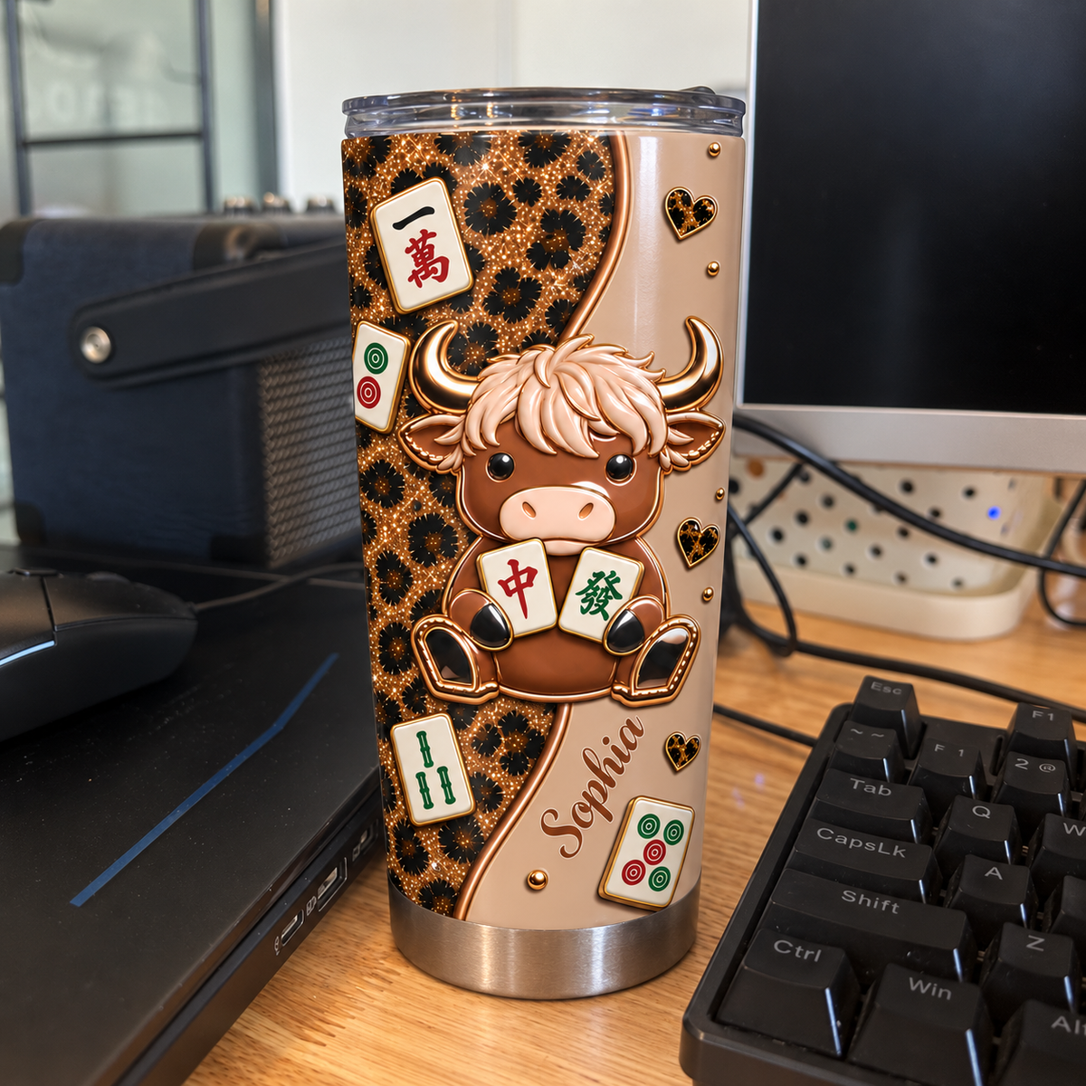 Custom name leopard print cow mahjong tumbler standing on wooden desk near computer keyboard.
