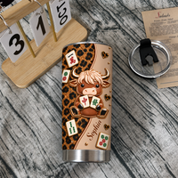 Leopard print cow mahjong tumbler lying on rustic wooden tabletop with wooden calendar and tumbler lid.