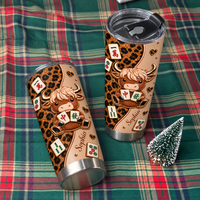 Two custom name leopard print cow mahjong tumblers on green plaid fabric next to miniature Christmas tree.