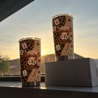 Two leopard print cow mahjong tumblers backlit by golden sunset on windowsill with box.