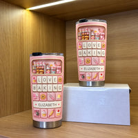 Two personalized baker gift tumblers in different sizes displayed on a wooden shelf inside a display box.