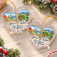 Two personalized acrylic heart ornaments displayed side-by-side on a rustic wooden table with pine tree accents.