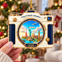 Fingers holding the travel memory keepsake ornament in front of a softly blurred holiday room.