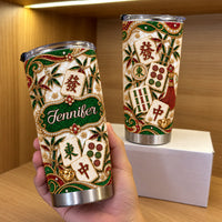 Hand holding personalized stainless steel tumbler with green bamboo mahjong print on wooden shelf next to a white box.