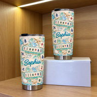 Two Mahjong Sea Glass Beach Tumblers stand on a wooden shelf inside a lit cabinet.
