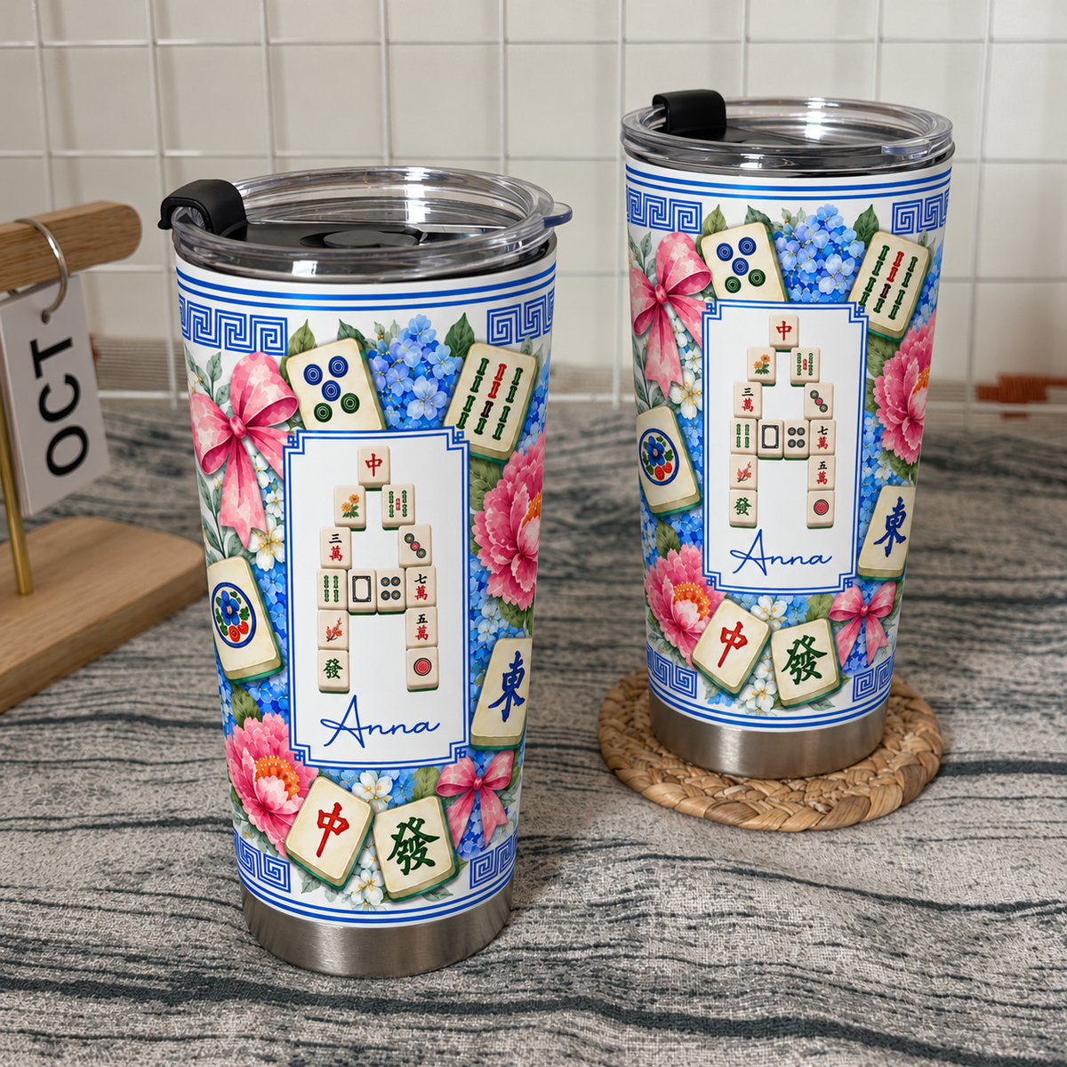 Two Mahjong Tile Number Floral Tumblers standing on a textured surface next to a wooden date block and coaster.