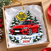 Personalized new driver acrylic ornament resting inside an open gift box lined with white tissue paper on a wooden surface