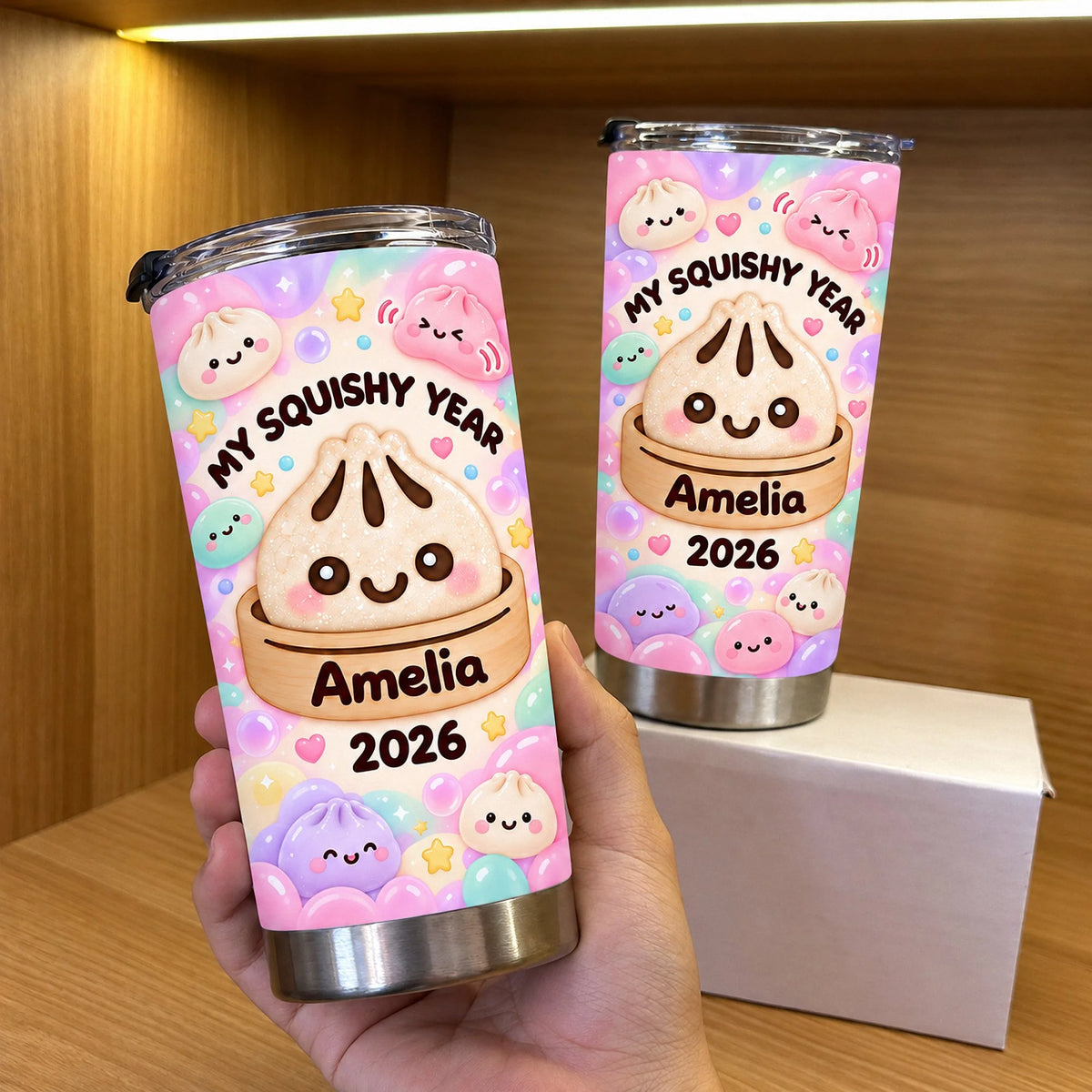 Hand holding a My Squishy Year Tumbler with pastel bao bun graphics, name Amelia, and year 2026.