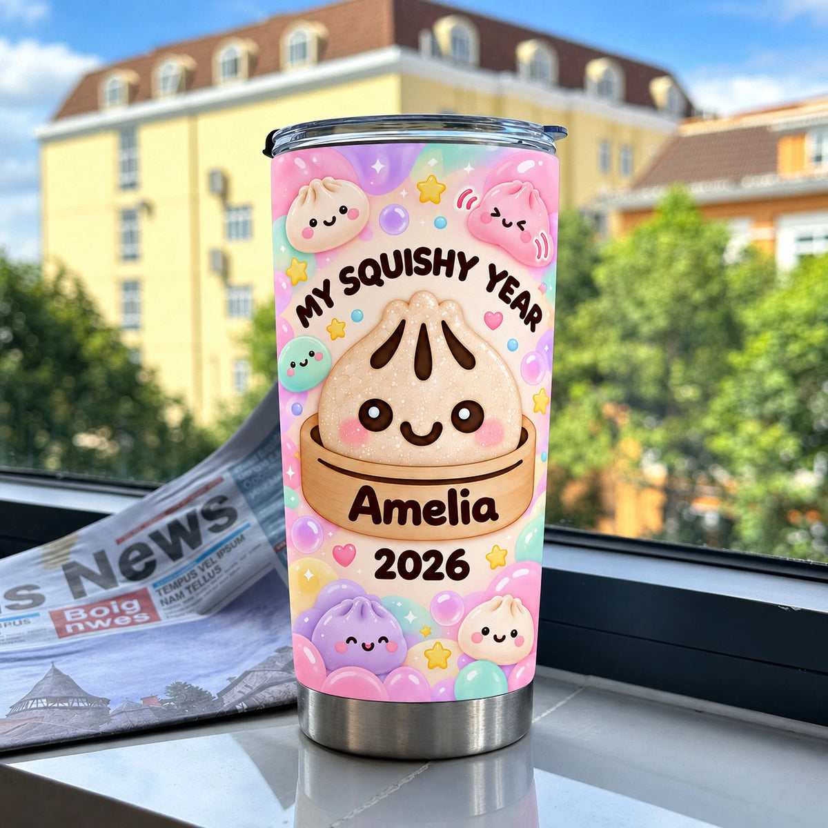 Stainless steel travel mug featuring kawaii bao bun art placed on a windowsill with a newspaper and buildings outside.