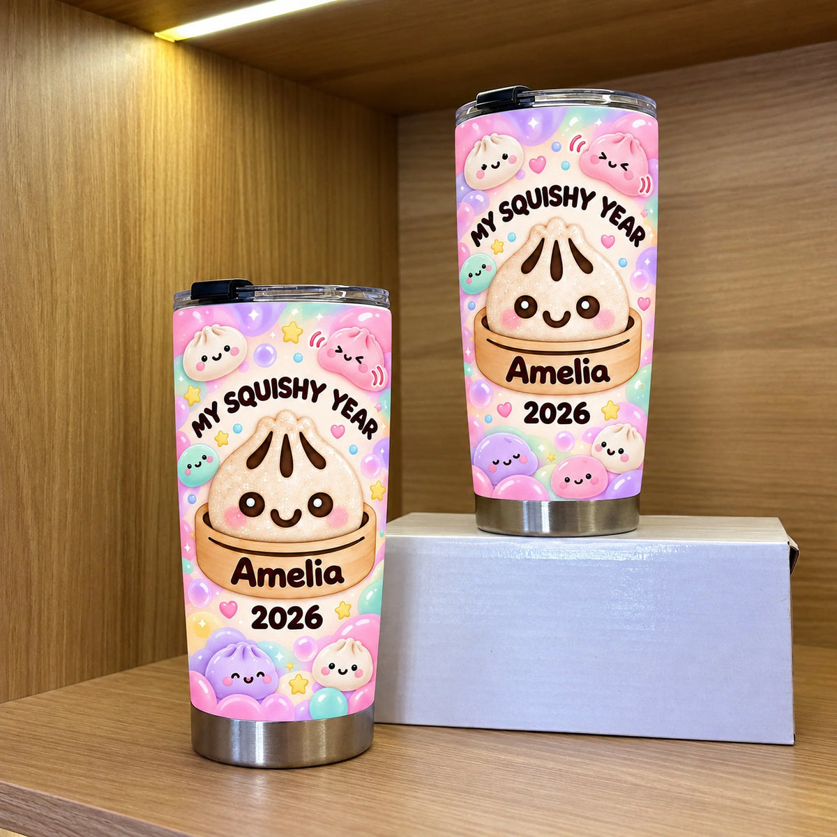 Two custom name tumblers featuring cute bao bun art displayed on wooden shelves with warm overhead lighting.