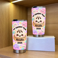 Two custom name tumblers featuring cute bao bun art displayed on wooden shelves with warm overhead lighting.