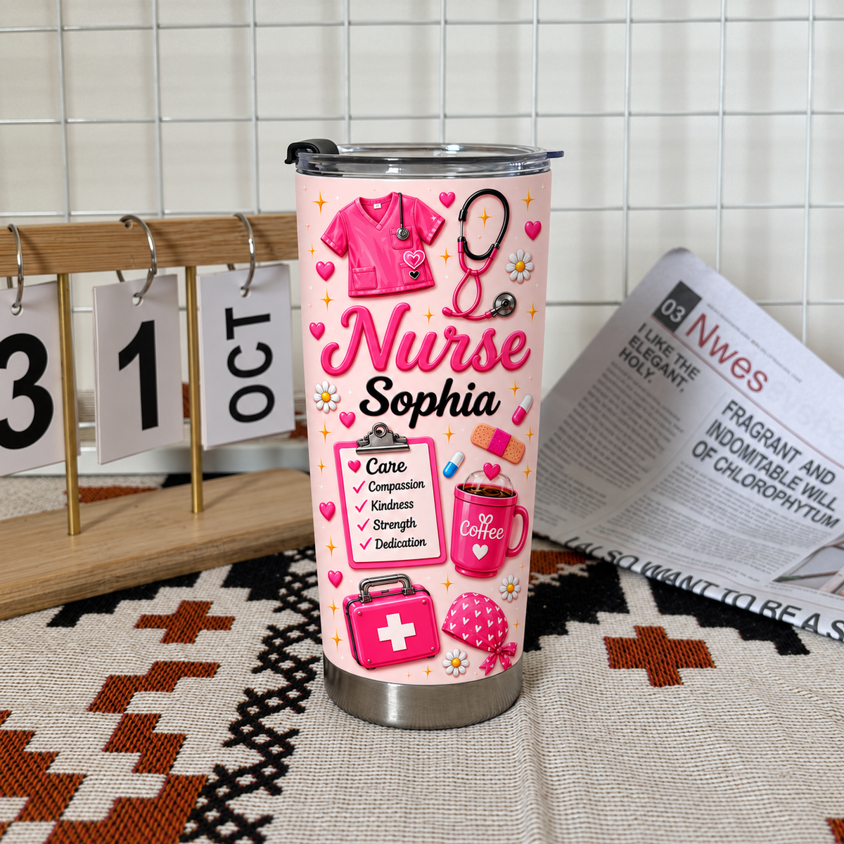 Pink custom nurse tumbler with 'Nurse Sophia' text and medical icons standing upright on a textured rug next to a calendar.