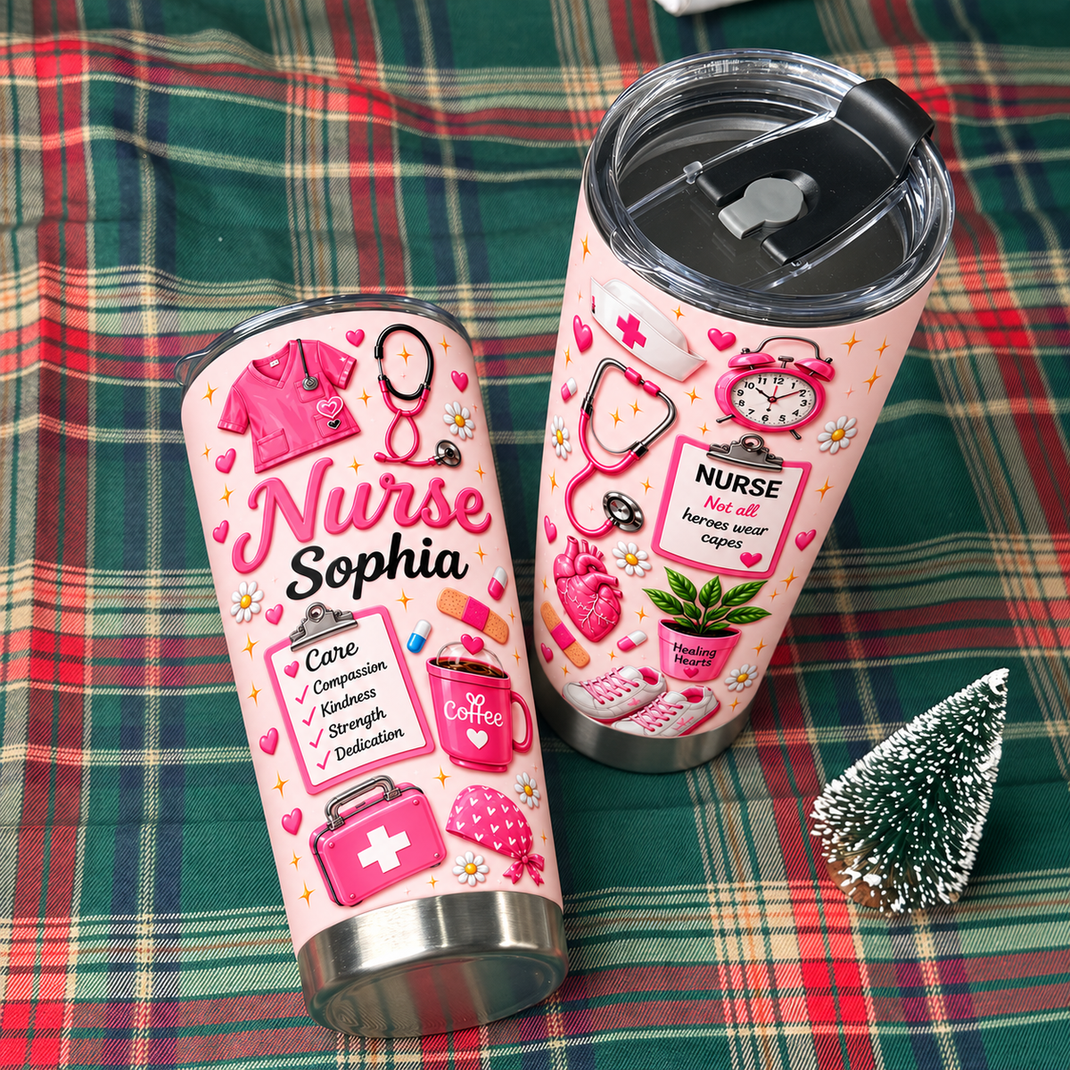 Two pink stainless steel nurse tumblers with custom name text displayed on a plaid blanket alongside a small pine tree.