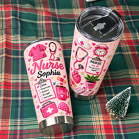 Two pink stainless steel nurse tumblers with custom name text displayed on a plaid blanket alongside a small pine tree.