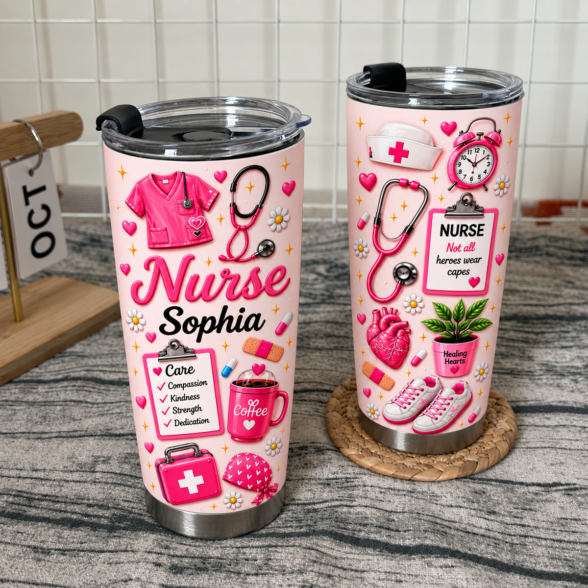 Two pink custom nurse tumblers with stethoscope and scrubs graphics sitting on a woven mat against a white grid wall.