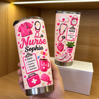 Hand holding pink stainless steel nurse tumbler with custom name Sophia and medical graphics against a wooden shelf.