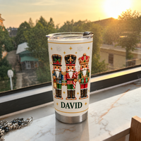 White stainless steel nutcracker Christmas tumbler with custom name David on windowsill overlooking greenery at sunset