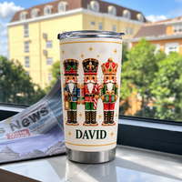 White stainless steel nutcracker Christmas tumbler with custom name David standing upright on windowsill with newspaper