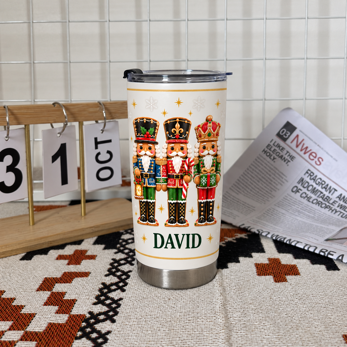 White stainless steel nutcracker Christmas tumbler with custom name David on patterned mat beside wooden calendar