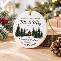 Personalized Christmas ornament resting on a wooden slice with snowy evergreen sprigs and pinecones.
