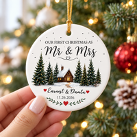 Hand holding a custom Mr & Mrs ceramic ornament in front of a softly lit Christmas tree.
