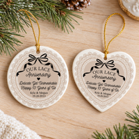 Round and heart 13th anniversary ceramic ornaments laid side by side on a wooden surface with gold strings and pine branches.