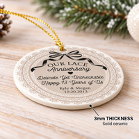 Close-up of a 3mm thick round ceramic lace anniversary ornament with a gold hanging string on a rustic wooden background.