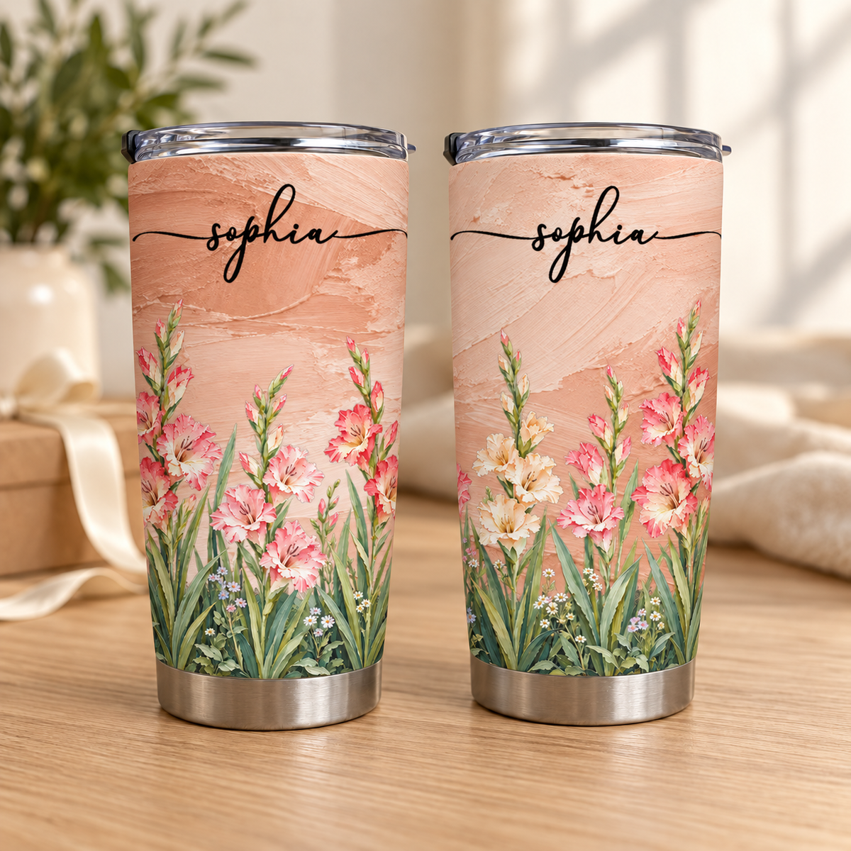 Two personalized birth flower tumblers with pastel peach background, floral meadow, and name Sophia standing upright.