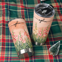 Two custom tumblers with pastel peach backgrounds and name Sophia resting on a green plaid fabric next to a mini tree.