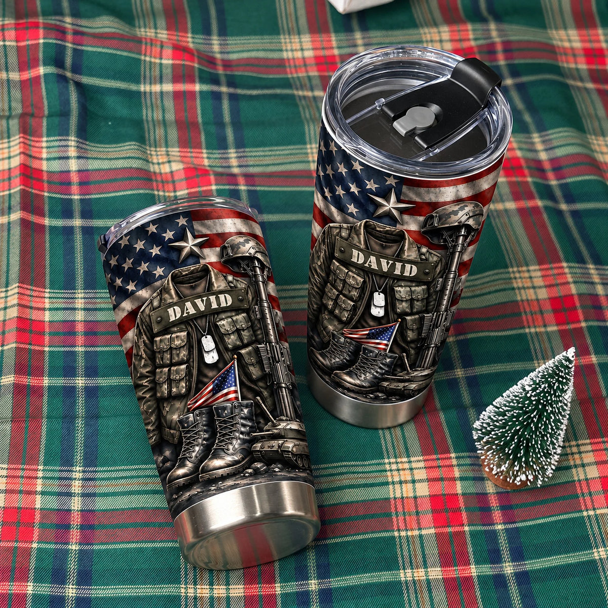 Two USA tactical drinkware tumblers on a green and red plaid blanket next to a small decorative pine tree.