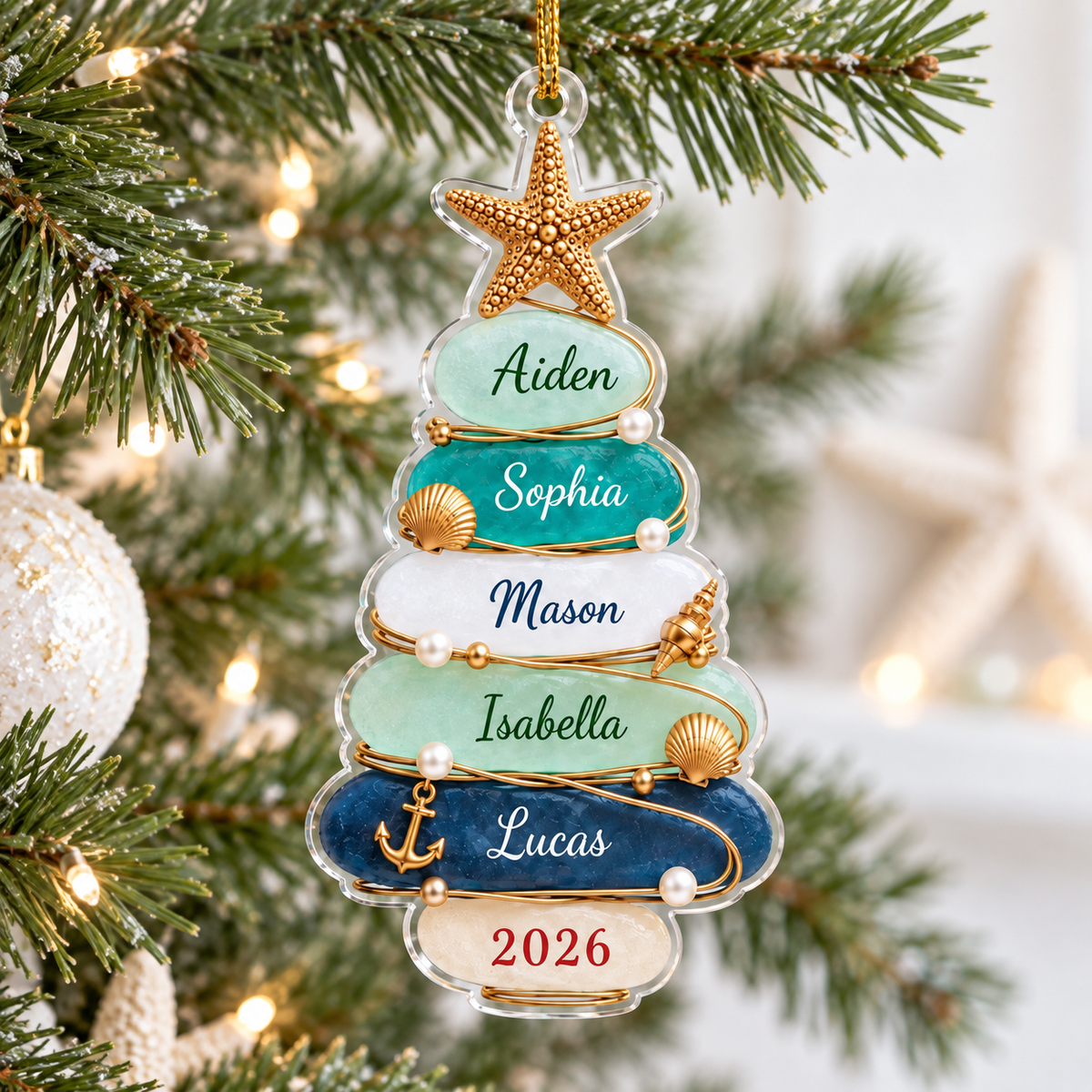 Personalized beach theme family Christmas ornament hanging on a pine tree branch with fairy lights.