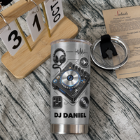 Insulated stainless steel travel tumbler with custom DJ design next to wooden desk calendar and lid.