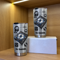 Two personalized DJ tumblers displayed on a wooden shelf inside a lit display box.