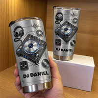 A person holding a personalized stainless steel DJ tumbler with a second tumbler on a white box behind.