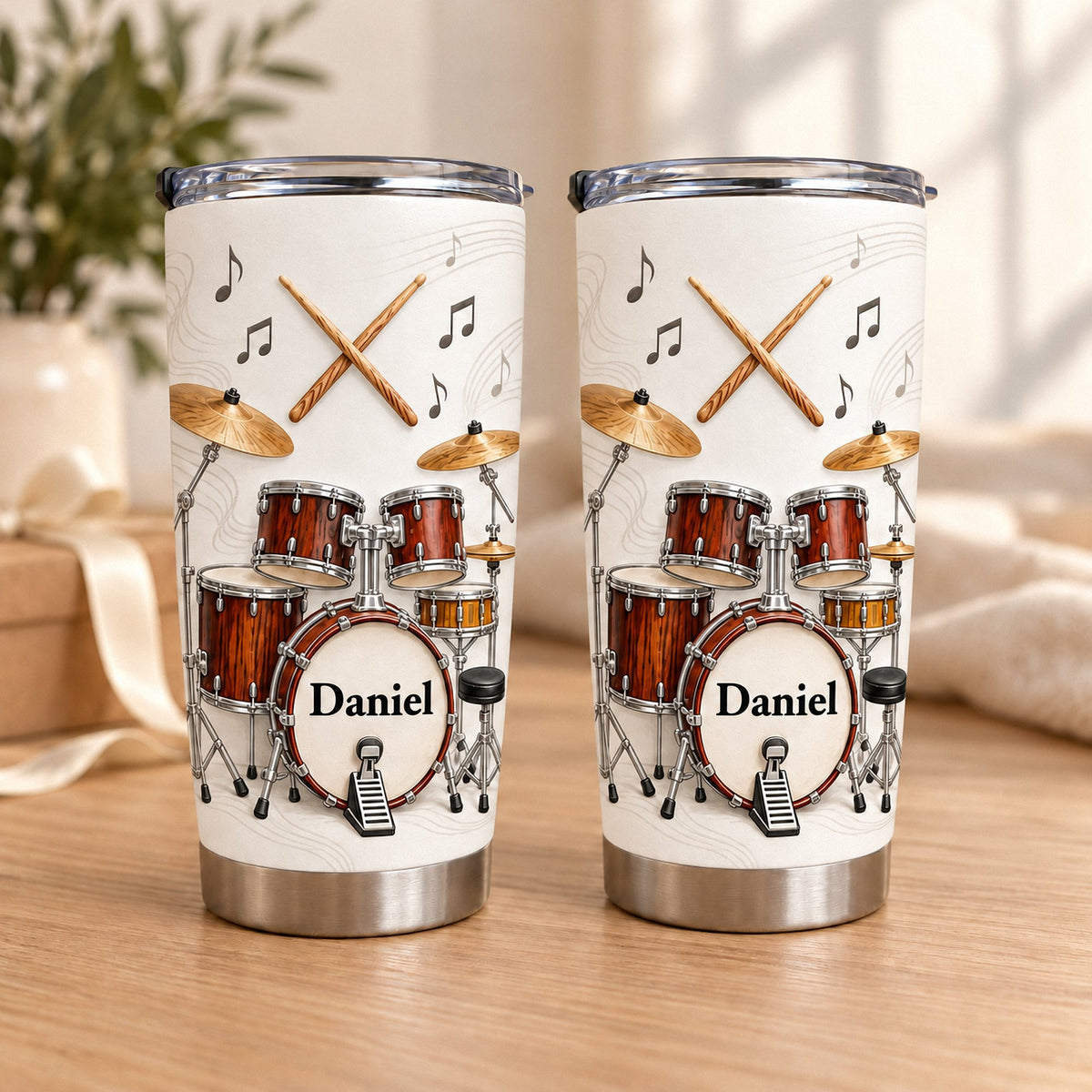 Two personalized drum kit tumblers showing red wood grain drum set design and custom name Daniel on wooden tabletop.