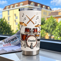 Personalized drum kit tumbler with red wood grain drum set graphic and custom name Daniel, outdoors on window ledge.