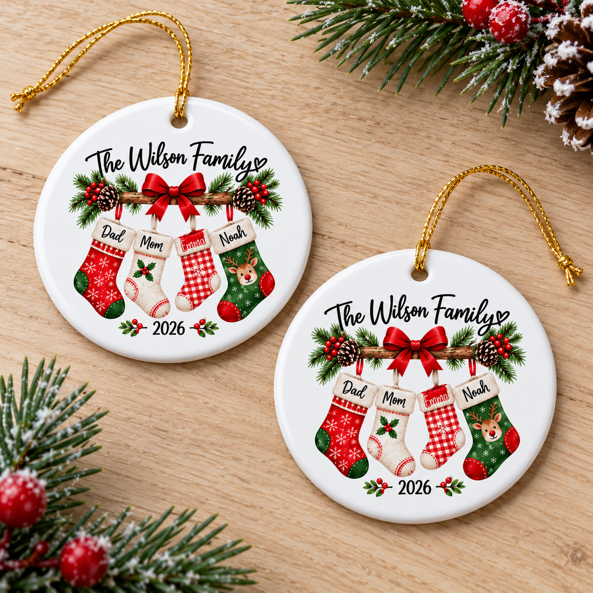 Two personalized ceramic ornaments resting on a wooden tabletop with pine branches.
