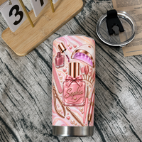 A personalized nail tech tumbler stands beside a wooden desk calendar and black lid on a textured rustic wooden surface.