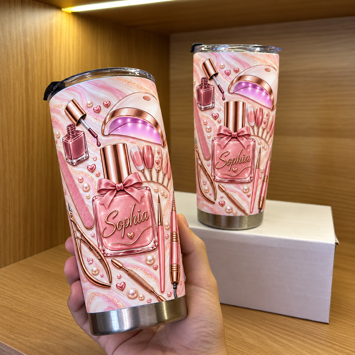 A hand holds a personalized nail tech tumbler showcasing a pink manicure tumbler design with rose gold nail art and a name