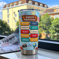 Personalized travel map tumbler on a window sill with a blurred building and green trees outside.