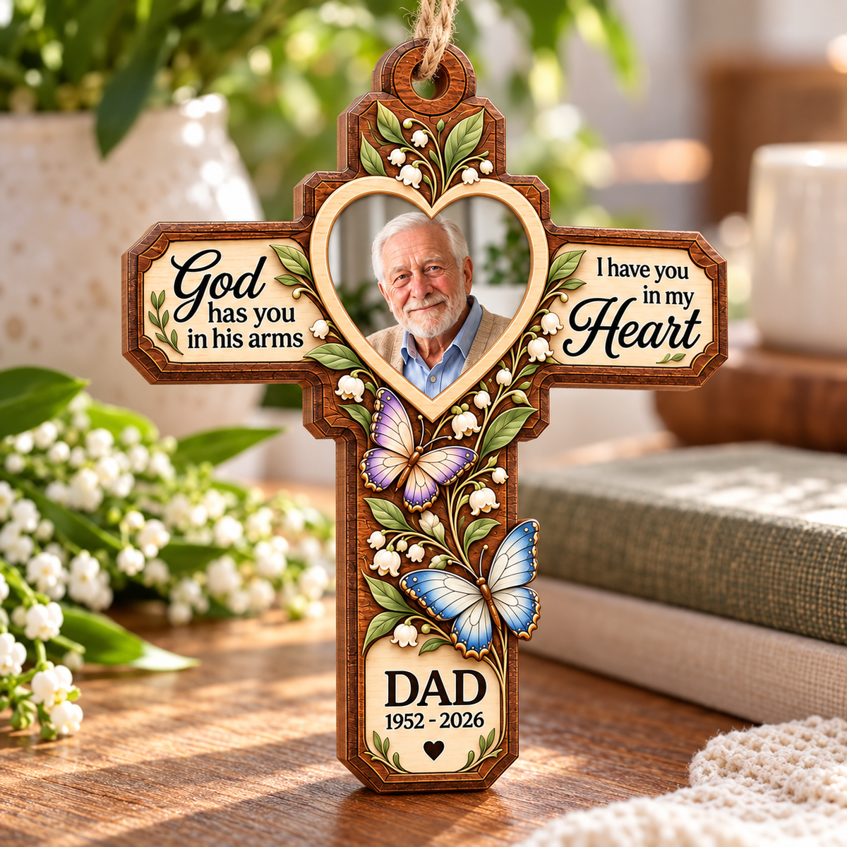 A personal keepsake Memorial Cross Wood Ornament displayed upright on a wooden table with greenery and a book.