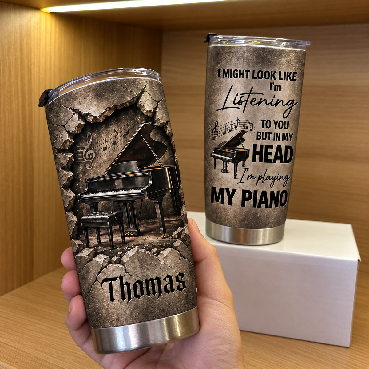 Hand holding personalized piano stainless steel tumbler showing custom name Thomas and grand piano graphic.