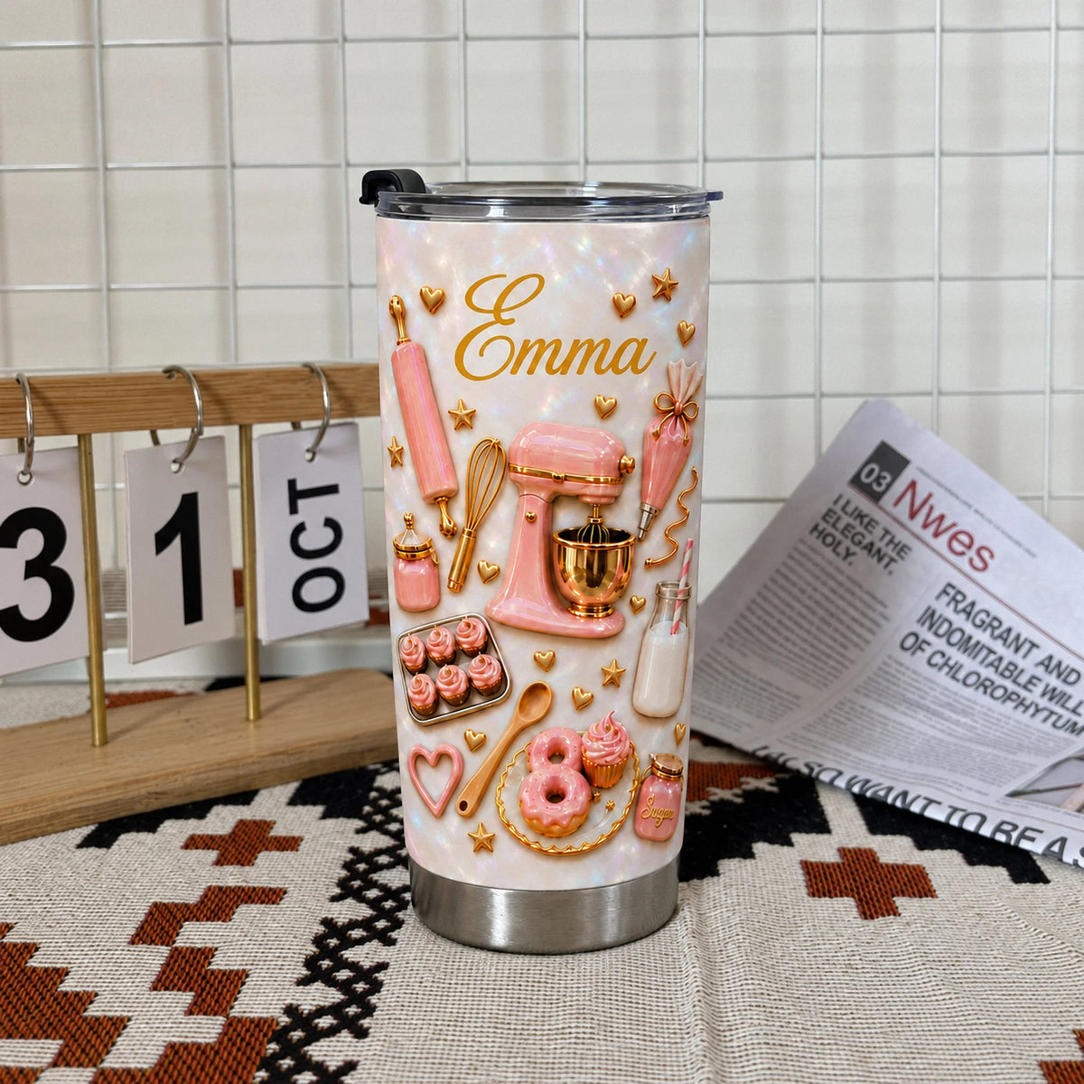 Pink baking theme tumbler displayed next to a wooden calendar and newspaper