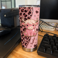 A single pink cow leopard print tumbler standing upright on a desk next to a keyboard and computer monitor.