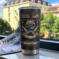 Black faux-leather insulated tumbler with police badge and thin blue line graphics standing upright near a window with an