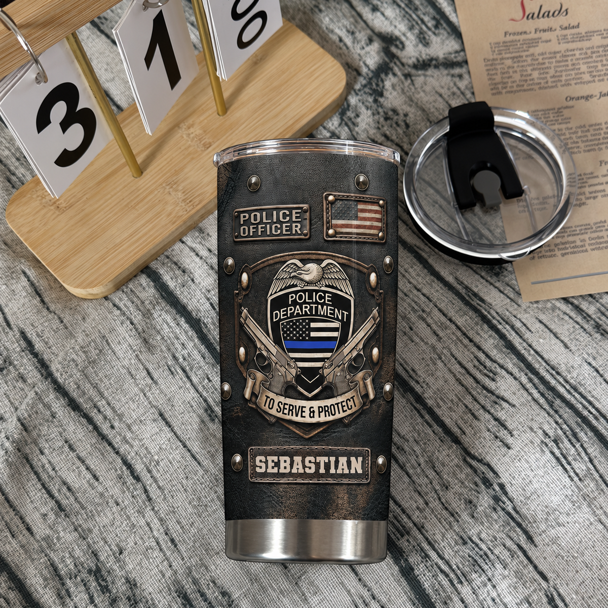 Personalized thin blue line cup with black faux-leather texture and name detail shown with its lid off on a textured wooden