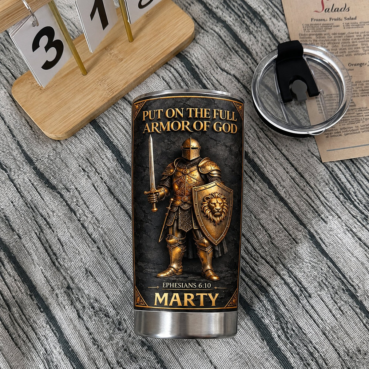 Personalized Full Armor Of God tumbler with gold knight and name Marty on wood table next to lid
