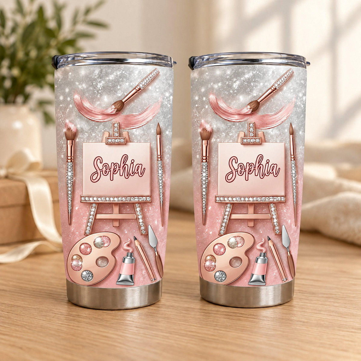 Two stainless steel tumblers with a rose gold glitter design showing artist tools, easel canvas, and the custom name Sophia.