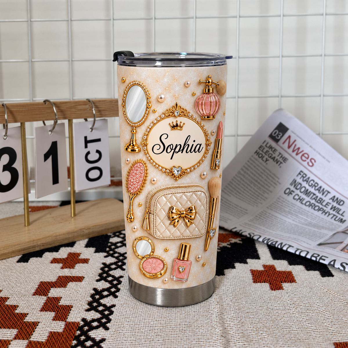 Single custom vanity tumbler with name Sophia standing on a patterned mat next to a calendar and newspaper.
