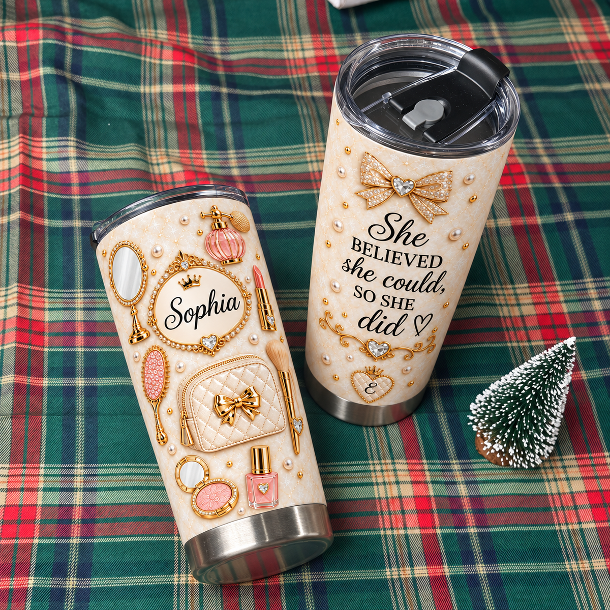 Two custom vanity design tumblers placed on a red and green plaid blanket next to a small holiday tree ornament.